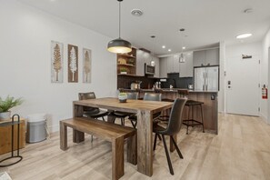 Een moderne keuken met een eethoek, met een houten tafel, stoelen en hanglampen.