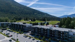 Un hotel de varios pisos con estacionamiento, rodeado por un paisaje montañoso.
