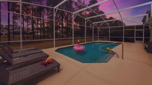 A covered outdoor swimming pool with lounge chairs and a slide. - Pool Oasis Near Disney, Games & TV, Family Time (Davenport)