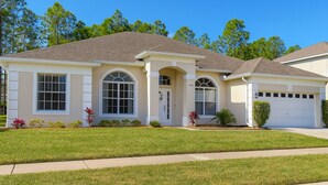 A single-story house with a front garage, a central entrance with an arched doorway, and a large window above the door. - Pool Oasis Near Disney, Games & TV, Family Time (Davenport)