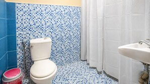 A bathroom with a toilet, shower curtain, and sink. - La Petite Pension (Puerto Princesa)