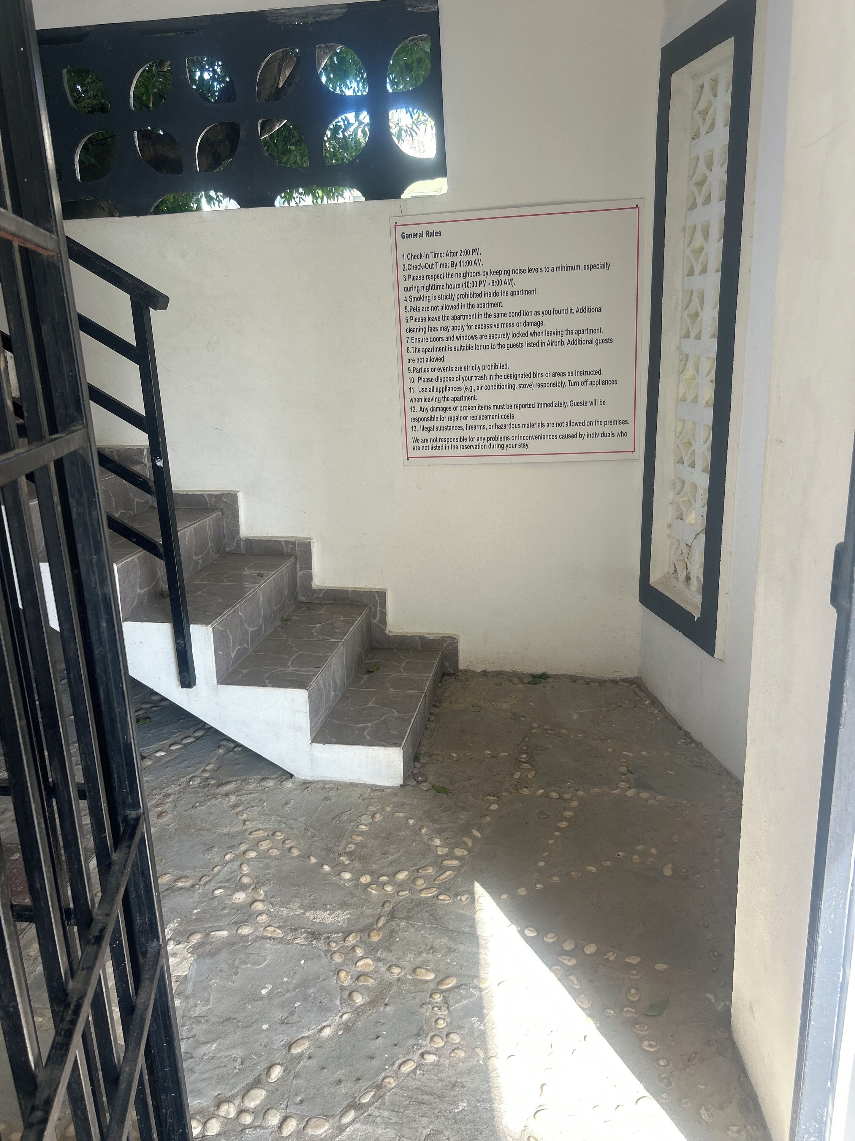 Eine Treppe führt zu einem Raum, in dem ein an der Wand befestigtes Schild allgemeine Regeln auflistet.