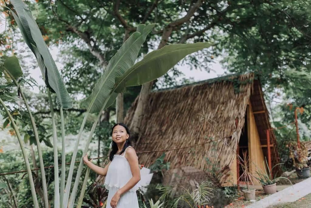 A rustic thatched-roof structure surrounded by lush greenery.