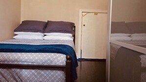 A single bed with patterned bedding, a wooden headboard, and a blue blanket.