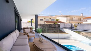 A modern balcony with a sofa, chairs, a table, and a potted plant. - T3 Casa Bonita Vacation Apartment in Nazaré (Sítio da Nazaré)