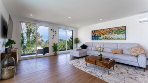 A modern living room with a sofa, coffee table, and artwork on the wall. - T3 Casa Bonita Vacation Apartment in Nazaré (Sítio da Nazaré)