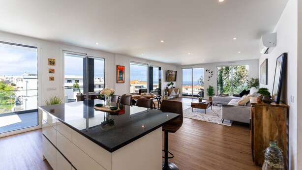A spacious living area with a large kitchen island, a dining area, and a sofa set. - T3 Casa Bonita Vacation Apartment in Nazaré (Sítio da Nazaré)