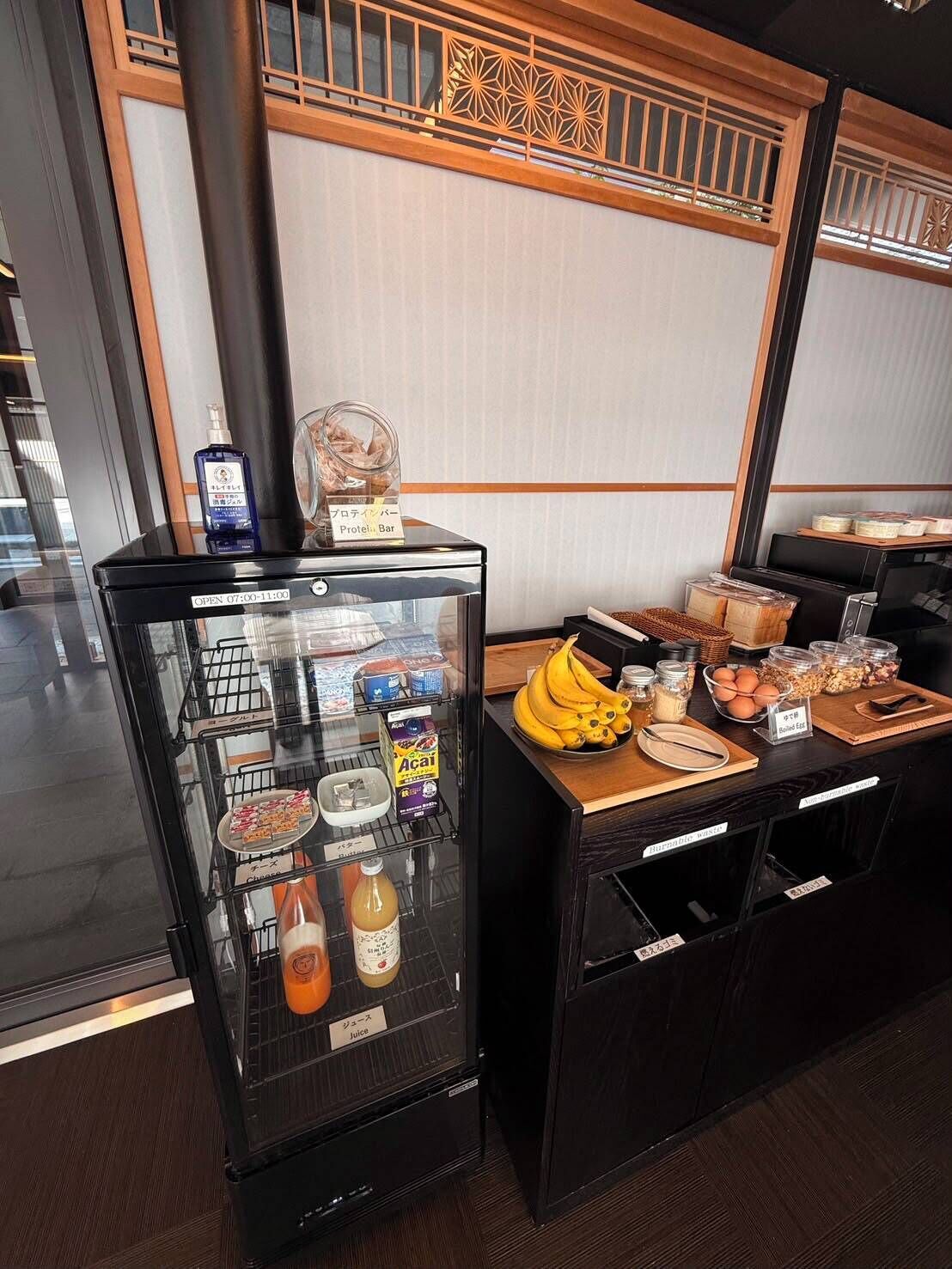 A breakfast bar with a refrigerated display case containing juice and a bottle of acai juice.