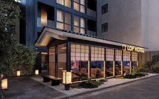 Un hotel con fachada moderna, grandes ventanales y una zona de estar visible en el exterior.