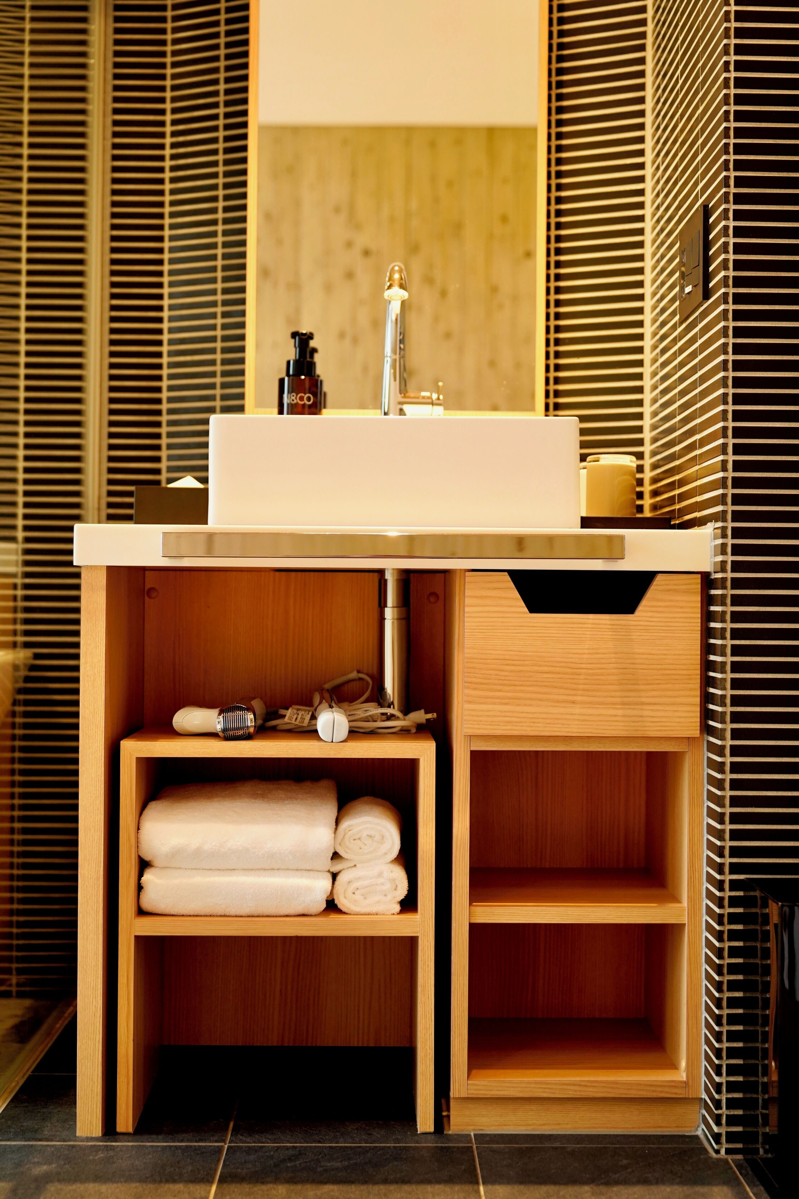 A modern bathroom with a wooden vanity, a sink, and a mirror.