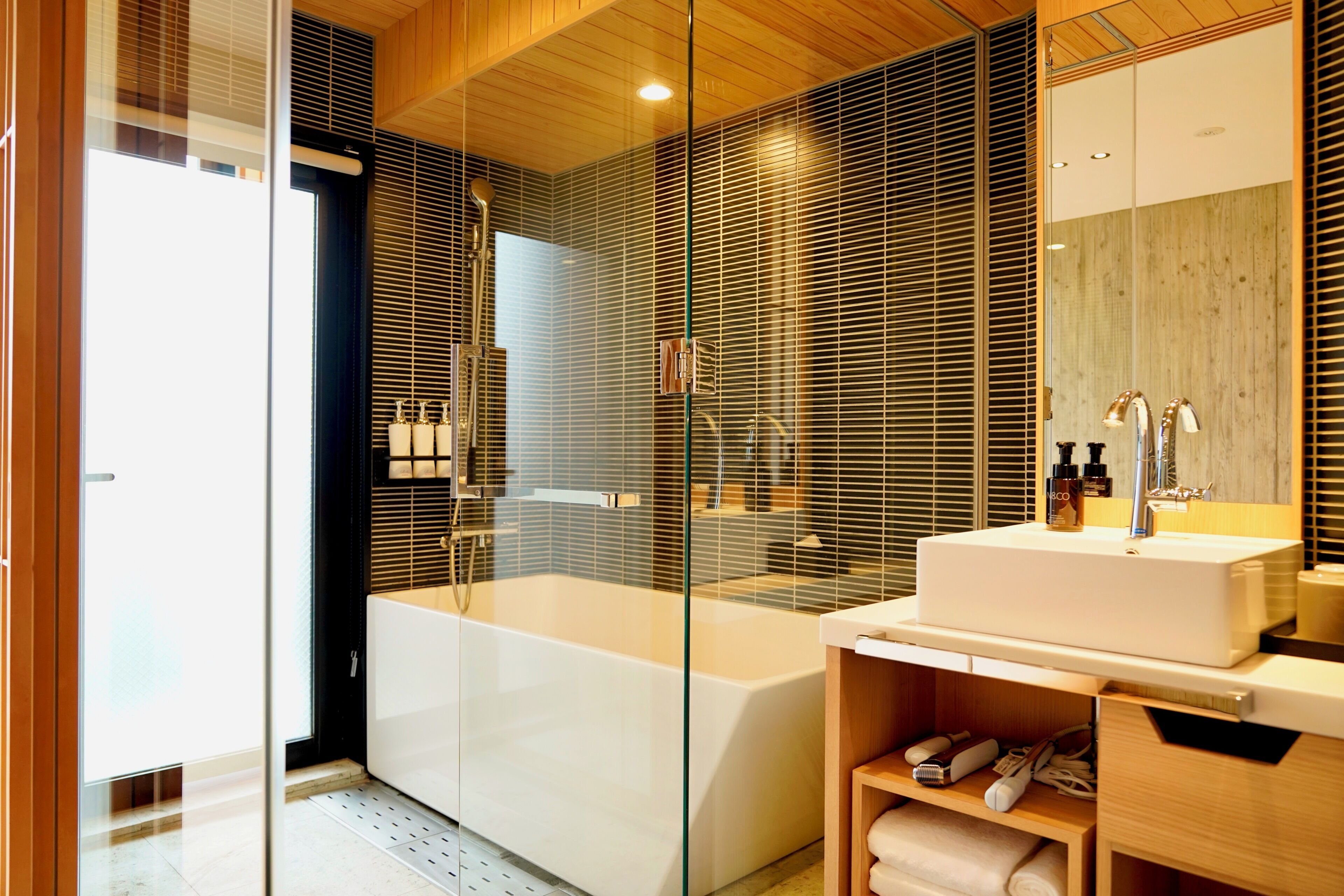 A modern bathroom with a glass-enclosed shower, a bathtub, and a vanity with a mirror.