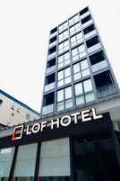 Un moderno edificio de hotel con un llamativo letrero 'LOF HOTEL', grandes ventanales y una estructura de varios pisos.
