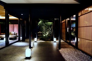 A corridor with glass doors, a pathway, and a small garden area with plants and a water feature.