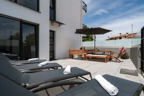 A rooftop terrace with lounge chairs, a wooden table, and an umbrella. - House Explorer Two (Istria - Funtana) (Funtana)
