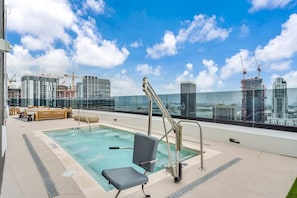 Una piscina sul tetto con vista sullo skyline cittadino, che include diversi grattacieli e gru da cantiere.