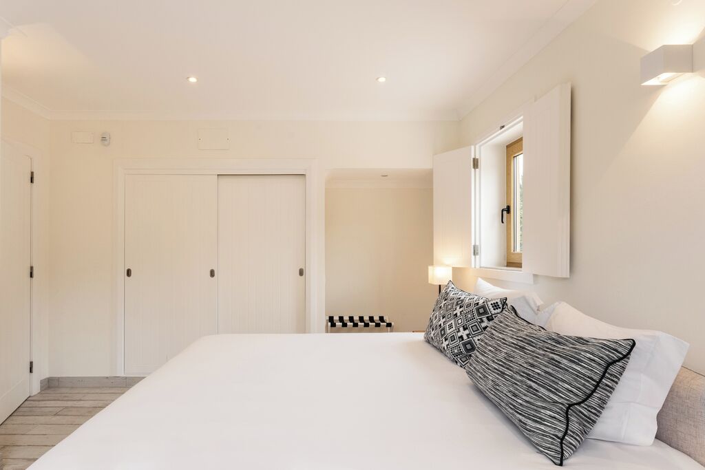Ein Hotelzimmer mit einem großen Bett, einem Schrank, einem Spiegel und einer kleinen Sitzecke.