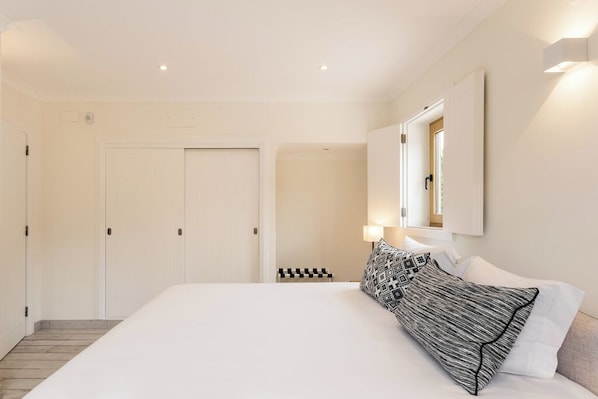 A hotel room with a large bed, a wardrobe, a mirror, and a small seating area. - Serene Suite w/ Balcony & Ocean View, Perfect for a Quiet Retreat (Lagos)