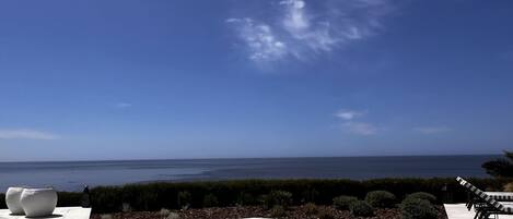 A pool with a clear view of the ocean and a clear sky.