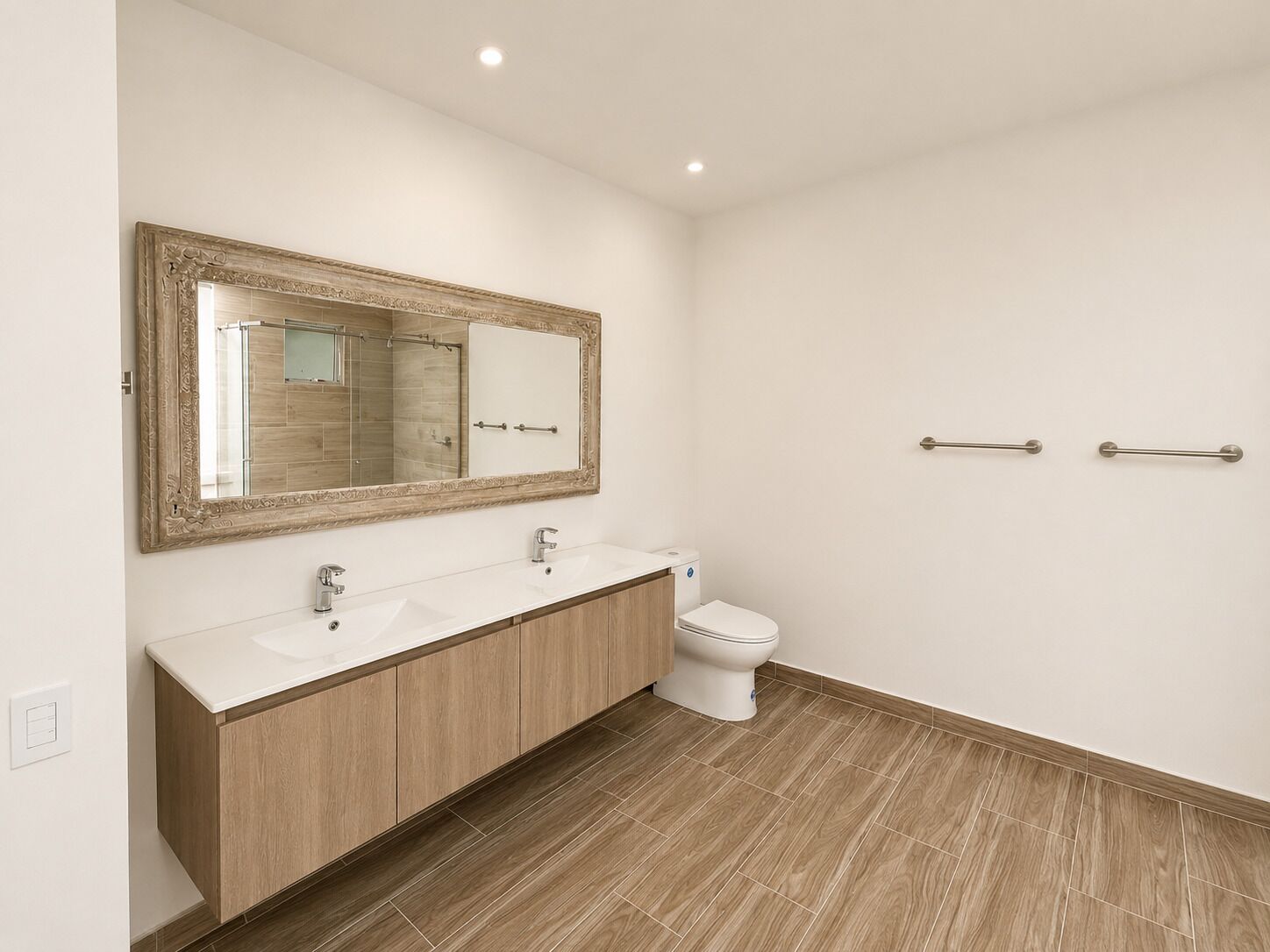 Ein modernes Badezimmer mit einem Doppelwaschbecken, einer Toilette und einem großen Spiegel.