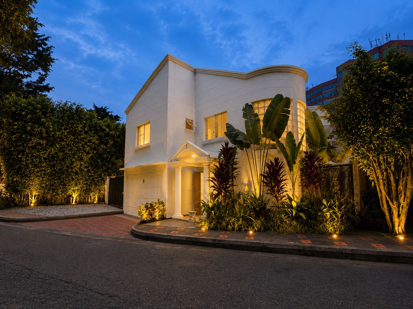 Un edificio a due piani con una facciata curva, un garage e un ingresso ben illuminato.