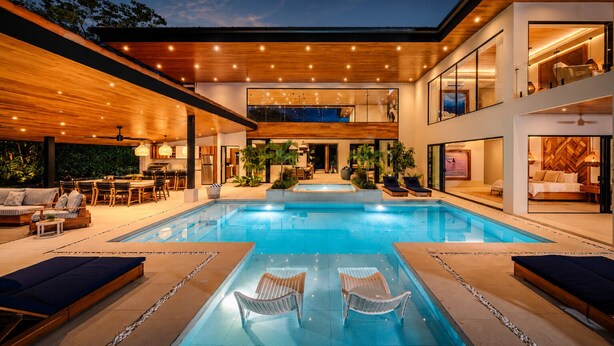 Een modern huis met zwembad, terras en eethoek.