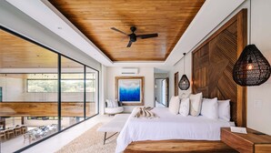 Een moderne slaapkamer met een groot bed, houten plafond en uitzicht op de omgeving.