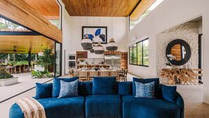 Een moderne woonkamer met een blauwe modulaire bank, een eethoek en grote ramen.