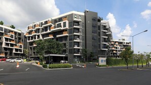 Um edifício residencial com várias andares, varandas, área de estacionamento e céu claro.