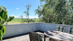 Eine Holzterrasse mit Tisch und Stühlen, mit Blick auf eine grüne Landschaft.