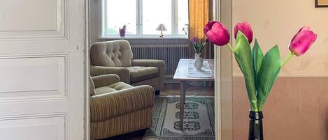Una sala de estar con un sofá, una mesa de centro y un florero con tulipanes.