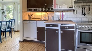 Eine kompakte Küche mit Geschirrspüler, Backofen und einer Essecke mit blauem Tisch und Stühlen.