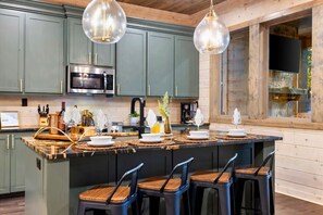 A kitchen with a central island, bar stools, and pendant lighting. - NEW! Pickleball, Hot Tub, ATV Trails, Outdoor Movies & Mini Golf (Broken Bow)