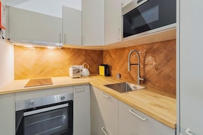 A modern kitchen with a herringbone-patterned backsplash, stainless steel appliances, and a wooden countertop. - Setúbal Downtown Fonte Nova, By Home Match (Setúbal)