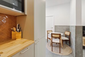 A kitchen with a wooden countertop, a knife block, and a dining area with two chairs and a round table. - Setúbal Downtown Fonte Nova, By Home Match (Setúbal)
