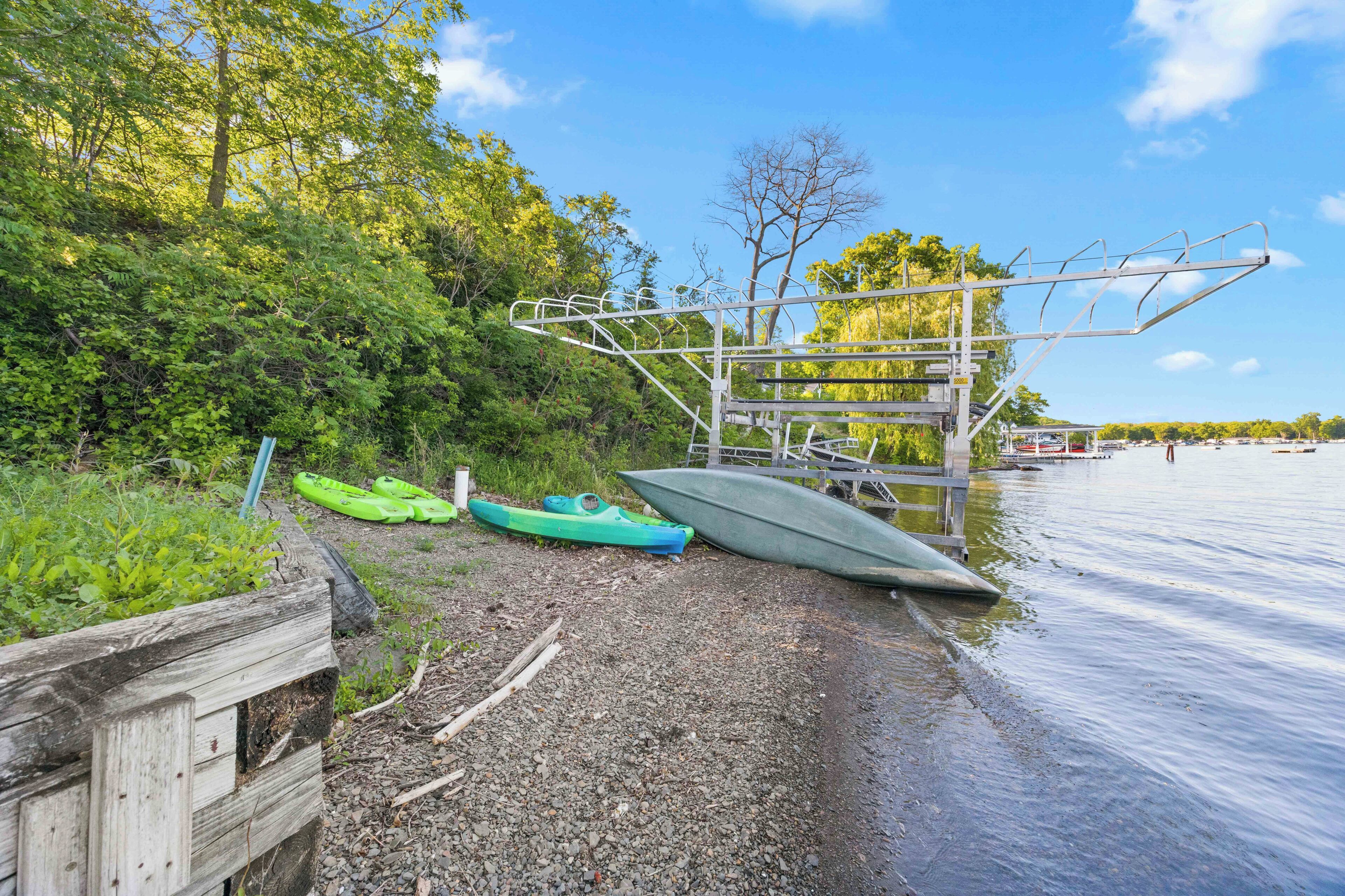 A wooden dock with kayaks and a metal structure by the water.