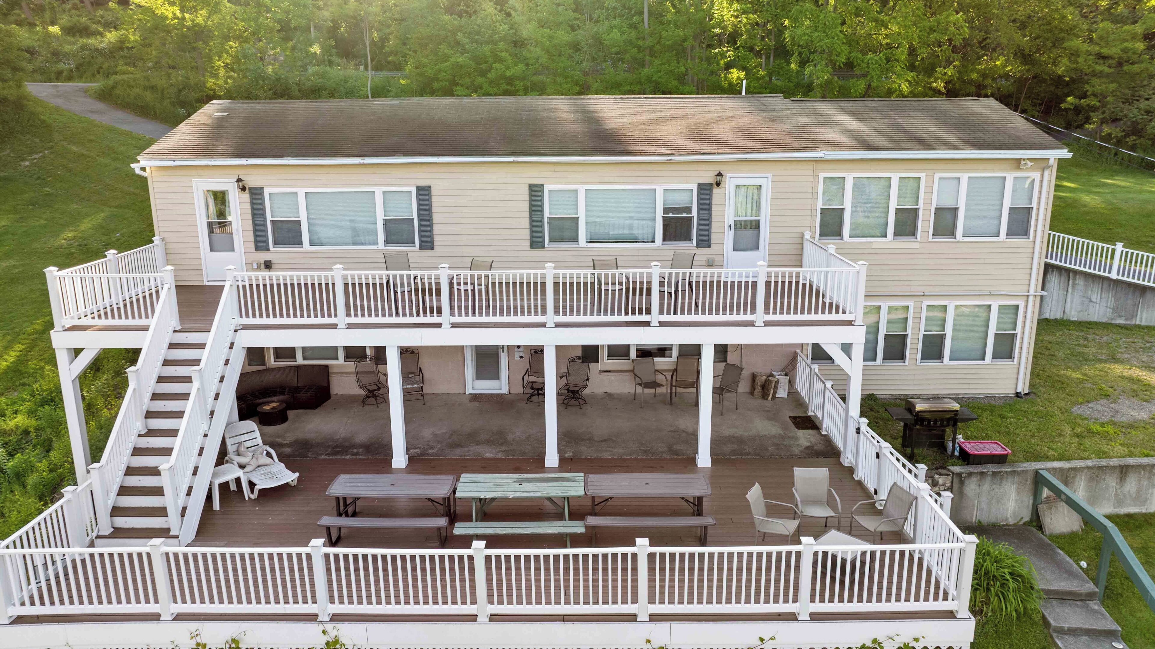 A two-story house with a covered deck, outdoor seating, and a staircase.