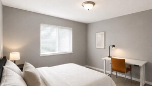 Ein Schlafzimmer mit Bett, Schreibtisch, Stuhl und Fenster.