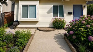 Ein zweistöckiges Haus mit Veranda, Briefkasten und einem Garten voller Hortensien.