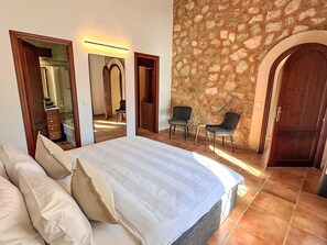 Ein Schlafzimmer mit einem großen Bett, einer Steinwand und einem Spiegel.