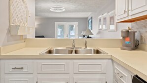 A kitchen with a double sink, white cabinets, a coffee machine, and a pendant light. - Spacious 2BR/2.5BA Beach Getaway | Relax & Unwind (North Myrtle Beach)