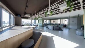 A modern office space with large windows, a central seating area, and a high ceiling with a grid-like structure. - Nik Perdizes: Premium Studio 400m from Nubank Parque (formerly Allianz Parque) (São Paulo)
