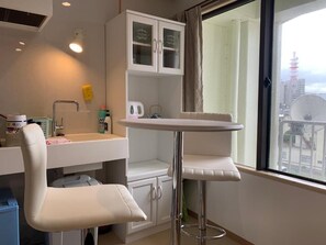 Ein kleines, modernes Badezimmer mit Waschbecken, Spiegel und Schrank. Ein Fenster bietet Blick auf Gebäude und einen Turm.