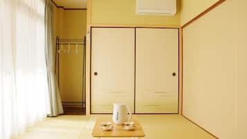 A room with a traditional Japanese sliding door, a small table with a kettle and cups, and a hanging clothes rack.