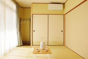 A room with a traditional Japanese sliding door, a small table with a kettle and cups, and a hanging clothes rack.