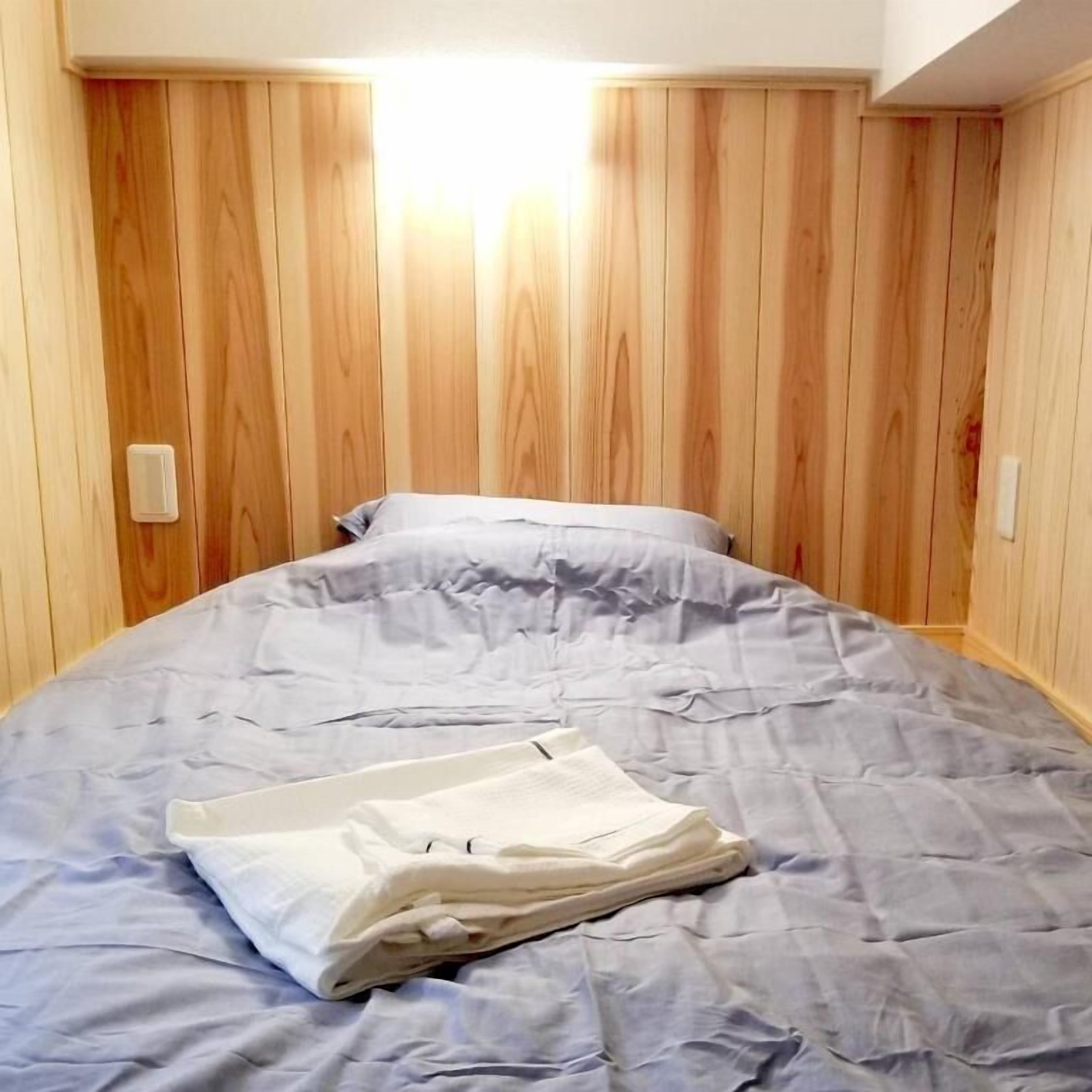 A room with a bed, wooden panel walls, and a light fixture.