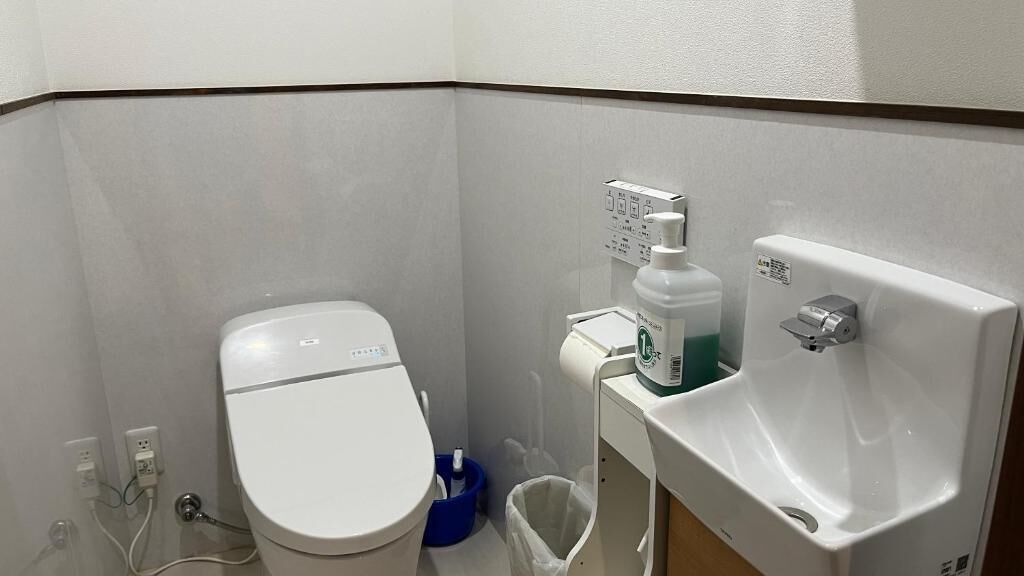 Un baño pequeño y funcional con inodoro, lavamanos y cubo de basura.