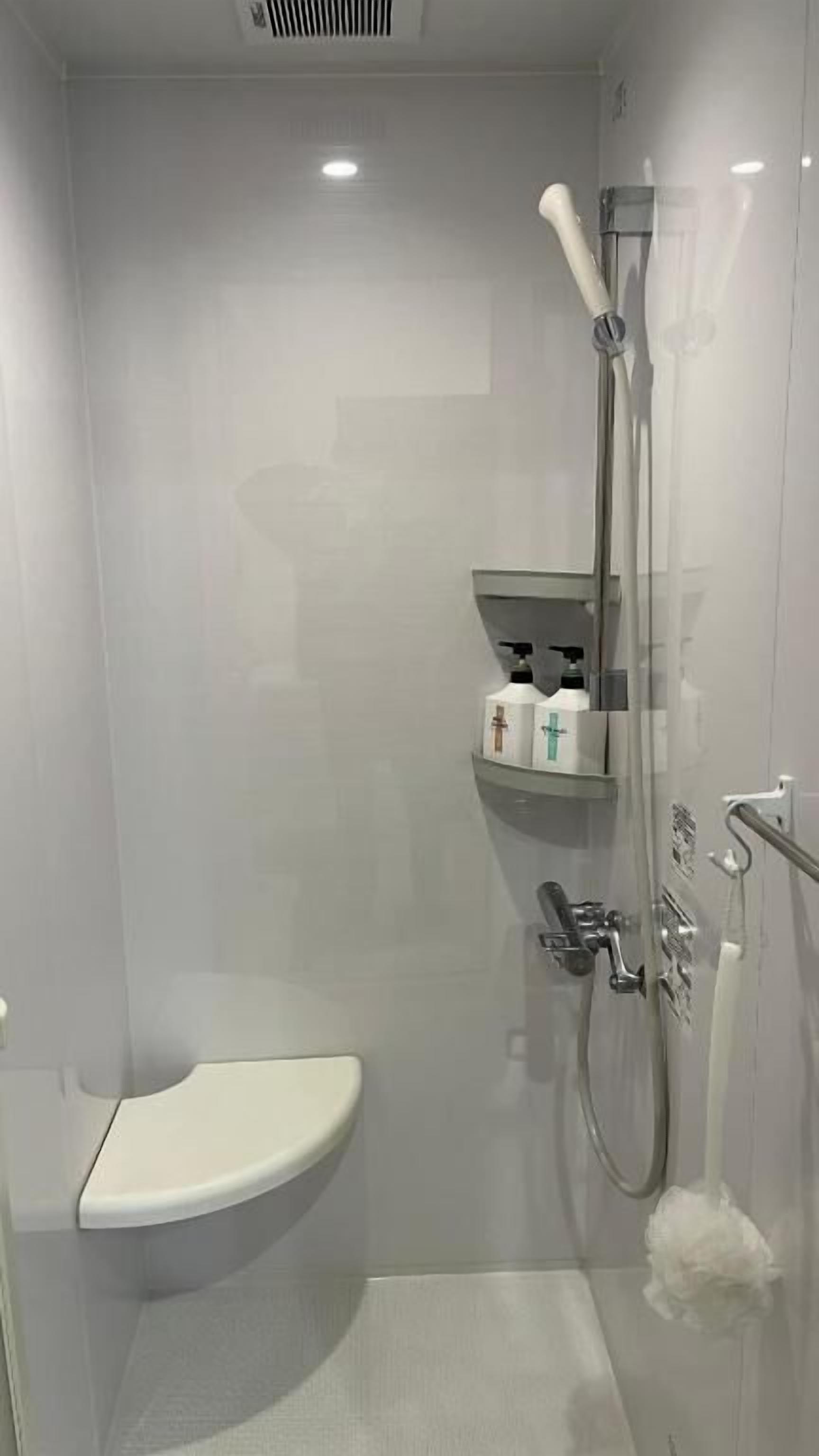 A modern bathroom with a glass-enclosed shower, a white sink, and a toilet.