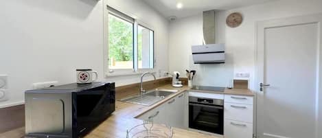 A compact kitchen with a microwave, sink, oven, and a window providing natural light.