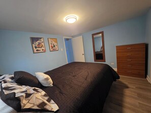 Ein Schlafzimmer mit einem Bett, einer Kommode und zwei Bildern an der Wand.