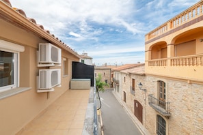 A narrow street flanked by buildings with balconies, air conditioning units, and a clear sky. - Apartment with parking in downtown Begur (Begur)
